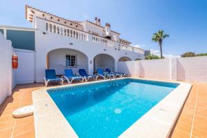 uma piscina com cadeiras azuis e uma casa em Bellavista Mar em Arenal d'en Castell