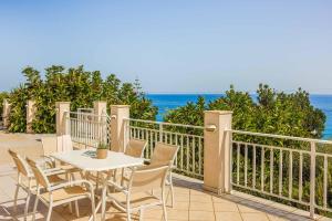 a table and chairs on a balcony with the ocean at Villa Angeliki Skala in Spathíon