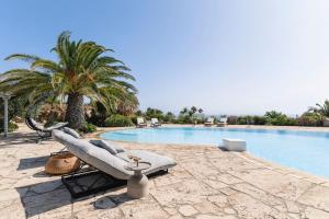 a pool with a lounge chair next to a palm tree at Verdemare West Villa in Mýkonos City