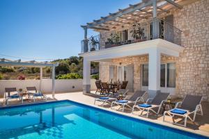 a villa with a swimming pool and a house at Evanthia by Vintage Travel in Fiskardo