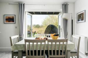 une salle à manger avec une table avec un bol de fruits dessus dans l'établissement Luxury property with spa access on a nature reserve Damselfly HM105, à Somerford Keynes