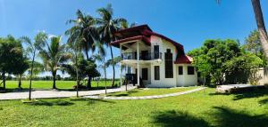 a white house with a red roof and palm trees at Aroma Villa Homestay in Polonnaruwa