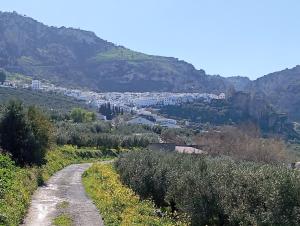 un camino de tierra en las montañas con una ciudad en Amapola Alojamiento Rural, en Zuheros