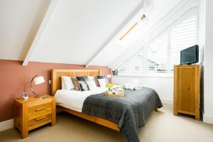 a bedroom with a bed and a tv in a attic at Lakeside property with spa on a nature reserve Bryony HM35 in Somerford Keynes +24 photos