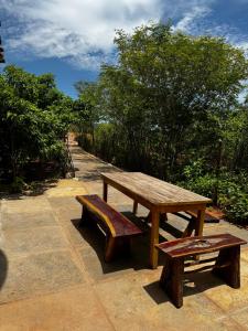 een houten picknicktafel en banken op een stoep bij Sertão do Luar in Jurubeba