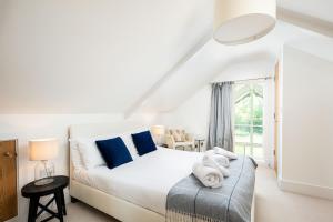 une chambre avec un lit blanc avec des oreillers bleus dans l'établissement Lakeside property with spa access on a nature reserve Kingfisher Lodge CW80, à Somerford Keynes 20 autres photos