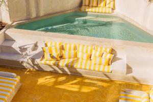 a swimming pool with two yellow and white chairs in it at Riad XO in Marrakesh