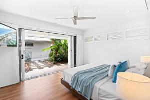a white bedroom with a bed and a sliding glass door at Belle Escapes - Namaste, Oasis in Palm Cove in Palm Cove +24 photos