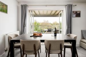 une salle à manger avec une table et des chaises et une fenêtre dans l'établissement Lakeview apartment with a Spa on a nature reserve Wigeon HM110, à Somerford Keynes