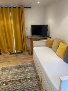 uma sala de estar com um sofá branco e cortinas amarelas em A lovely one bed flat in North Finchley em Finchley