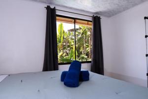 a blue elephant sitting on a bed in front of a window at Blu House Nature & Tours in Chachagua