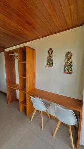 escritorio de madera con 2 sillas blancas en una habitación en Pousada Belas Águas, en Praia de Araçatiba