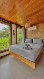 una camera da letto con un grande letto con pareti e finestre in legno di Pousada Belas Águas a Praia de Araçatiba