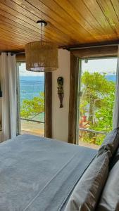 um quarto com uma cama e vista para o oceano em Pousada Belas Águas em Praia de Araçatiba