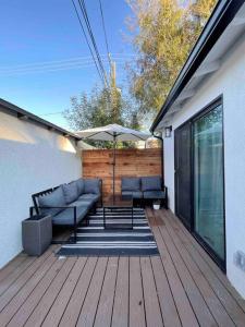 una terraza de madera con sofá y sombrilla en Modern Two Bedroom Two Bath W/ Parking and Laundry, en Los Ángeles