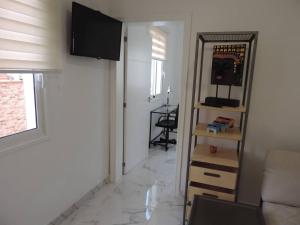 a living room with a couch and a television on a wall at One bedroom appartement with wifi at San Cristobal de La Laguna 3 km away from the beach in Las Lagunas