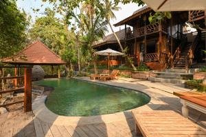 a swimming pool in front of a house at Tegal Campuhan Retreats in Munggu