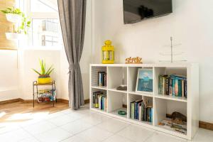 un estante de libros blanco con libros y TV en la pared en One bedroom appartement at Corralejo 200 m away from the beach with wifi, en Corralejo