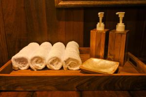 a wooden shelf with four towels and two bottles of soap at Tegal Campuhan Retreats in Munggu