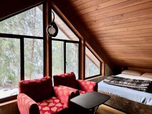 a bedroom with a bed and two chairs in a room with windows at Chalet at Rainier Lodge (0.4 miles from the entrance) in Ashford