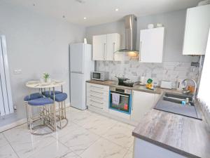 a kitchen with white appliances and a table and stools at Pass the Keys 5 Min Walk Free Parking Coop Live and Ethiad Arena in Manchester