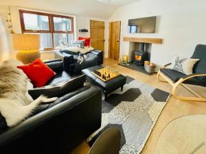 a living room with a black leather couch and a chess at Stags Hide - Aviemore 