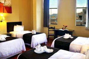 a hotel room with three beds with towels on them at Casona Plaza Hotel Centro in Puno