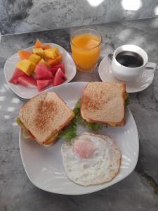 ein Frühstücksteller mit einem Sandwich, Eiern und Obst in der Unterkunft The Secret Eco Lodge in Tortuguero
