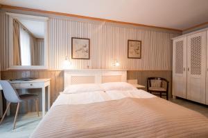 Schlafzimmer mit einem großen weißen Bett, einem Schreibtisch und einem Schreibtisch in der Unterkunft Hotel Maxant in Frymburk
