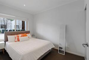 a white bedroom with a bed and a window at Percy Escape just a walk to Newtown cafes and shops in Geelong