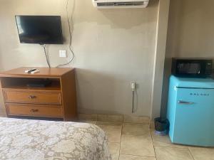 a bedroom with a bed and a television and a dresser at Apple Valley Motel in Apple Valley