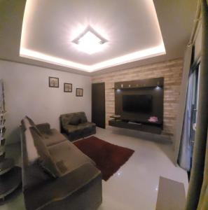 ein Wohnzimmer mit einem Flachbild-TV und einem Sofa in der Unterkunft Lindo sobrado a beira rio in Piçarras