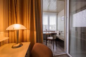 a room with a desk and a table with a lamp at Hotel Maxant in Frymburk