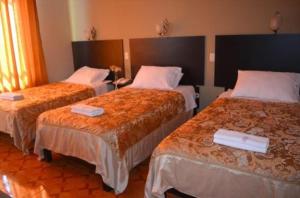 a hotel room with three beds in a room at HOTEL CASA REAL in Tacna