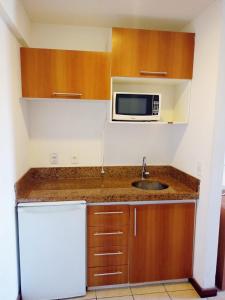 a small kitchen with a sink and a microwave at Mirador Vista Mar 110 in Natal