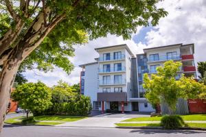 an apartment building with trees in front of it at Essence Apartments Chermside in Brisbane