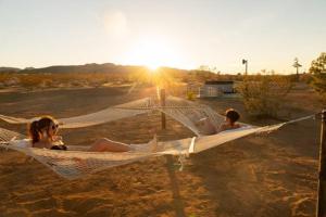 two people laying in a hammock on a beach at Dagger Tree Oasis l Integratron 5Bed and Cowboy Pool in Landers