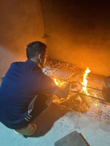 un hombre está sentado junto a un fuego en Sapa Shalom Homestay en Sa Pa