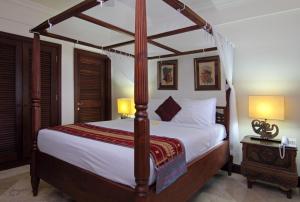 a bedroom with a large bed with a wooden canopy at Villa Ocean in Tanah Lot