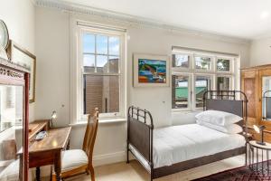 una camera con letto, scrivania e finestre di Eclectic Art Deco Apartment in great location a Sydney