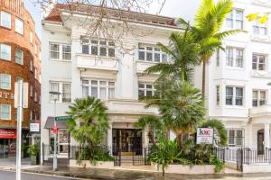 a white building with palm trees in front of it at Eclectic Art Deco Apartment in great location in Sydney