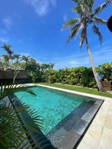 a swimming pool with a palm tree in the background at Villa Ocean in Tanah Lot