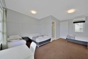Dieses weiße Zimmer verfügt über 3 Betten und ein Fenster. in der Unterkunft Ned Kelly's Motel in Maryborough