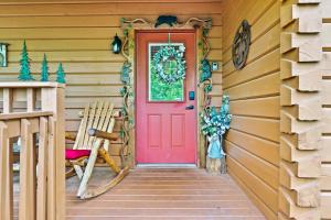 a red door on the front of a wooden house at New! Cozy, ADA Accessible, Family Cabin w/ Hot Tub in Sevierville