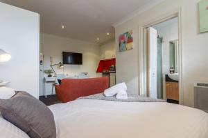 a bedroom with a white bed and a red chair at Studio Apartment in the heart of Fitzroy in Melbourne