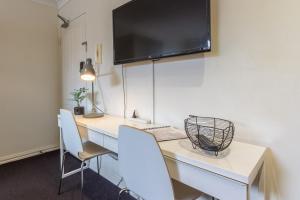 a room with a desk with two chairs and a television at Studio Apartment in the heart of Fitzroy in Melbourne