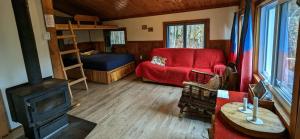 a living room with a red couch and a bed at Chalets Aux Berges du Lac Castor in Saint-Paulin
