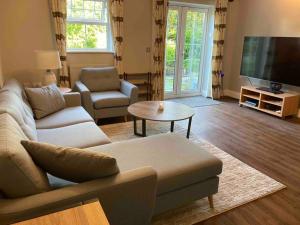 uma sala de estar com um sofá e uma televisão em Stunning Racecourse Townhouse for Royal Ascot em Winkfield