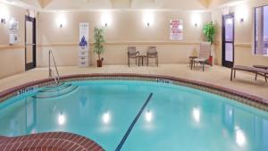una piscina en una habitación de hotel con sillas y mesas en Holiday Inn Express Denton UNT TWU, an IHG Hotel en Denton