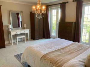 a bedroom with a bed and a dresser and a mirror at Stunning Racecourse Townhouse for Royal Ascot in Winkfield
